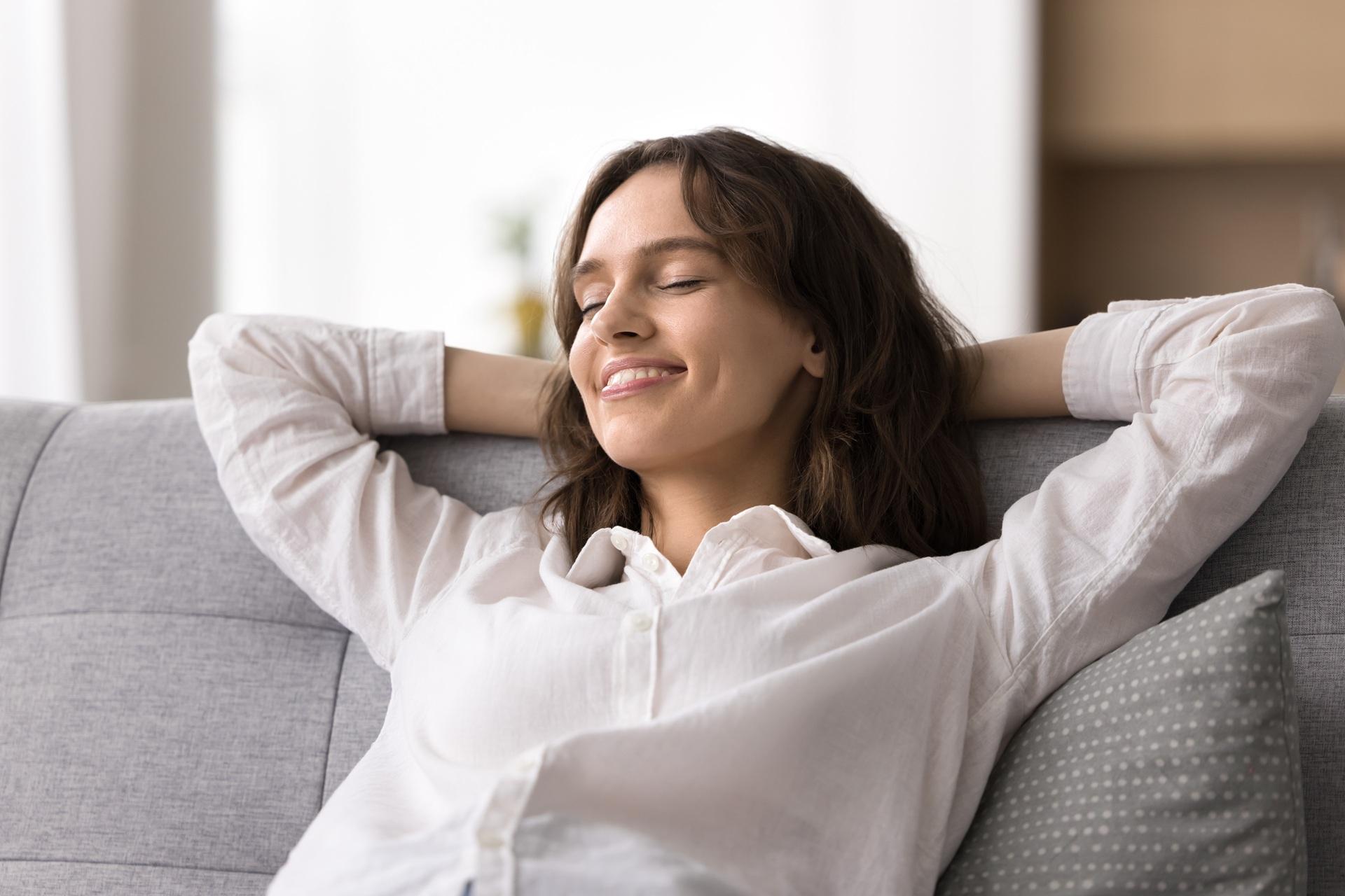 Lächelnde Frau entspannt sich komfortabel auf dem Sofa | Wandpaneel